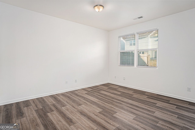 unfurnished room with dark wood-style flooring and baseboards