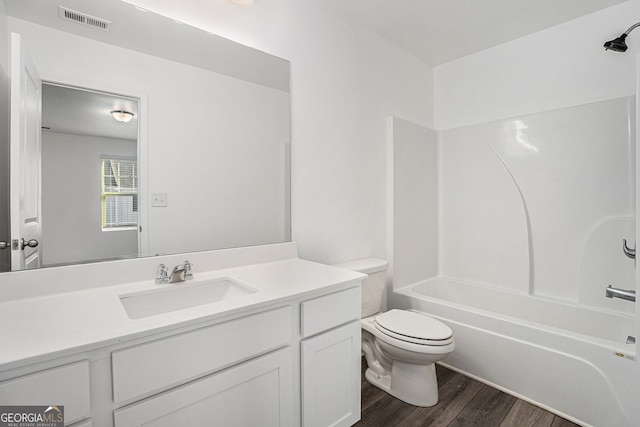 bathroom featuring wood finished floors, toilet, vanity, and shower / tub combination