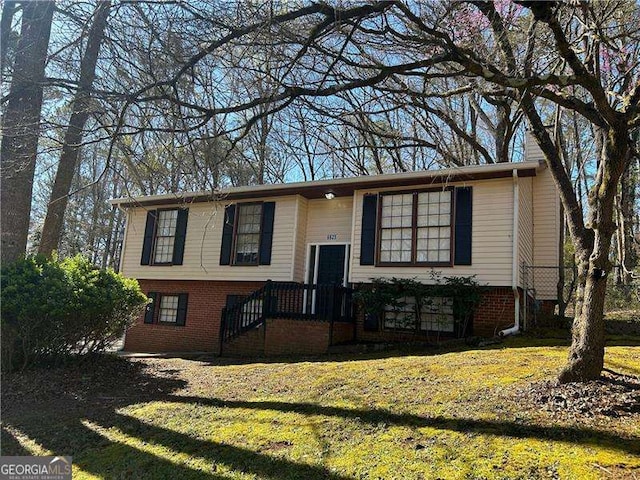 split foyer home with a front yard and brick siding