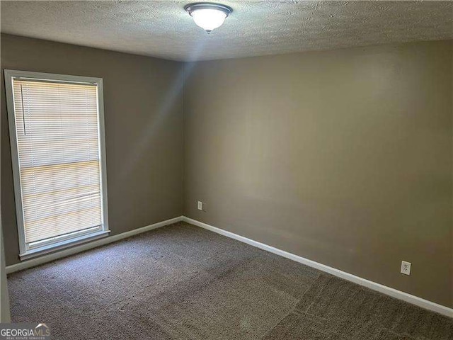 carpeted empty room featuring baseboards and a textured ceiling