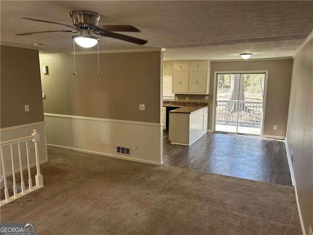 unfurnished living room with visible vents, ceiling fan, a textured ceiling, crown molding, and dark colored carpet