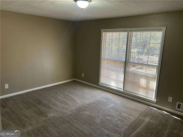 carpeted spare room with baseboards and a textured ceiling