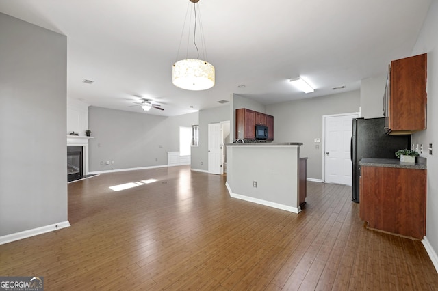 3258 Welmingham Dr SW, Atlanta, GA 30331 - kitchen with brown cabinetry, dark wood-type flooring, a glass covered fireplace, black appliances, and a ceiling fan