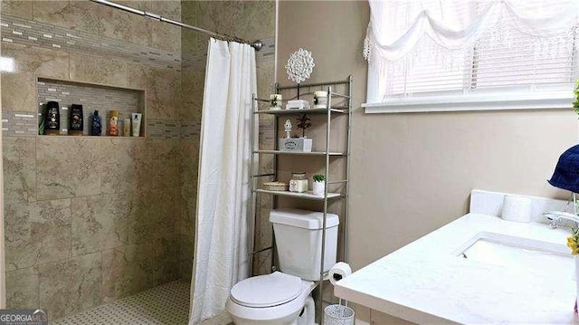full bathroom featuring a sink, toilet, and tiled shower