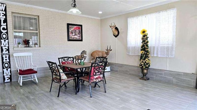 dining area featuring wood finished floors, brick wall, and crown molding