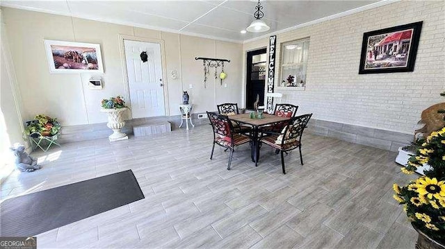 dining area featuring brick wall and wood finished floors