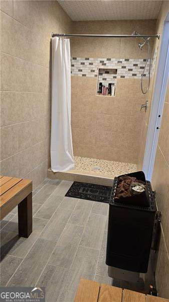 full bathroom with tiled shower and tile walls