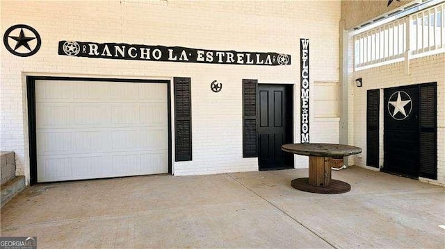 entrance to property with a garage and brick siding