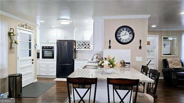 kitchen featuring ornamental molding, a kitchen breakfast bar, black appliances, and a sink