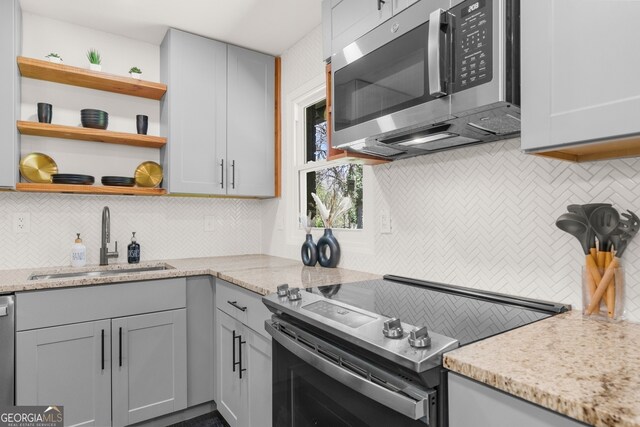 kitchen with open shelves, backsplash, appliances with stainless steel finishes, and a sink