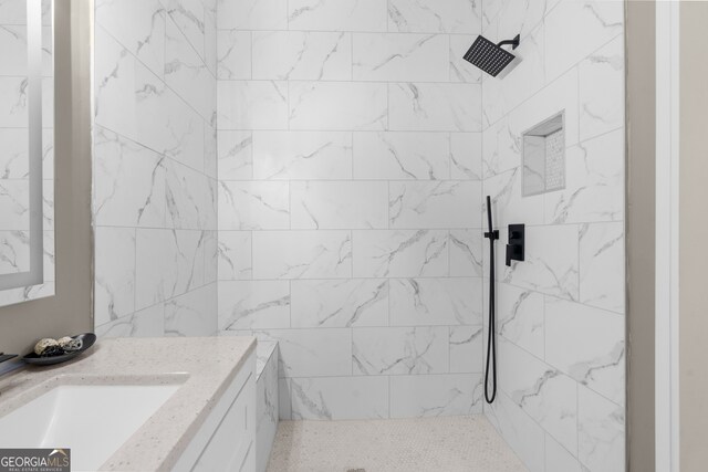 bathroom with a tile shower and vanity