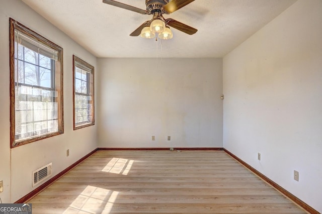 unfurnished room with visible vents, ceiling fan, baseboards, light wood-style floors, and a textured ceiling