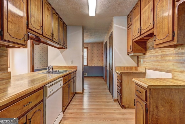 kitchen featuring a sink, a textured ceiling, brown cabinetry, light countertops, and dishwasher