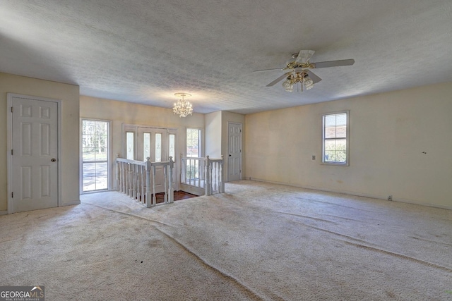 carpeted spare room with ceiling fan with notable chandelier and a textured ceiling