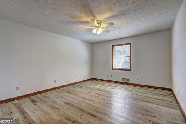 empty room with baseboards, wood finished floors, visible vents, and ceiling fan