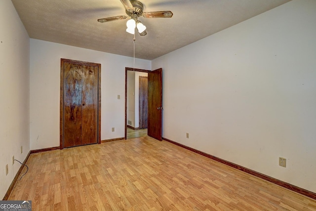 unfurnished bedroom featuring a textured ceiling, light wood-type flooring, baseboards, and a ceiling fan