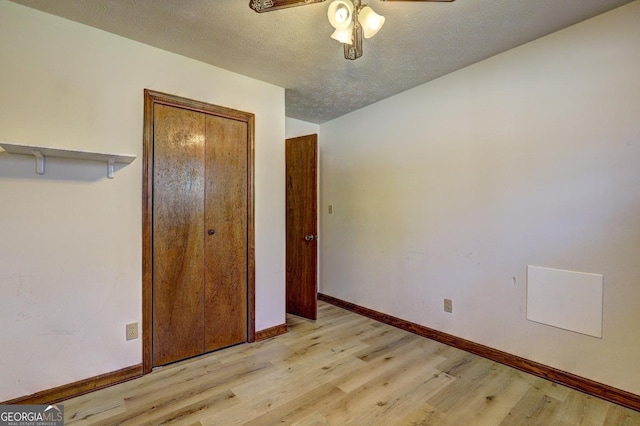 unfurnished bedroom featuring a closet, baseboards, a textured ceiling, and light wood-style floors
