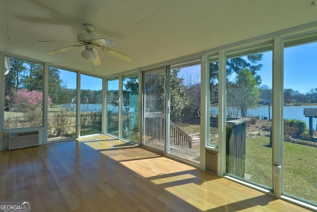 unfurnished sunroom with a wall mounted air conditioner, ceiling fan, and a water view