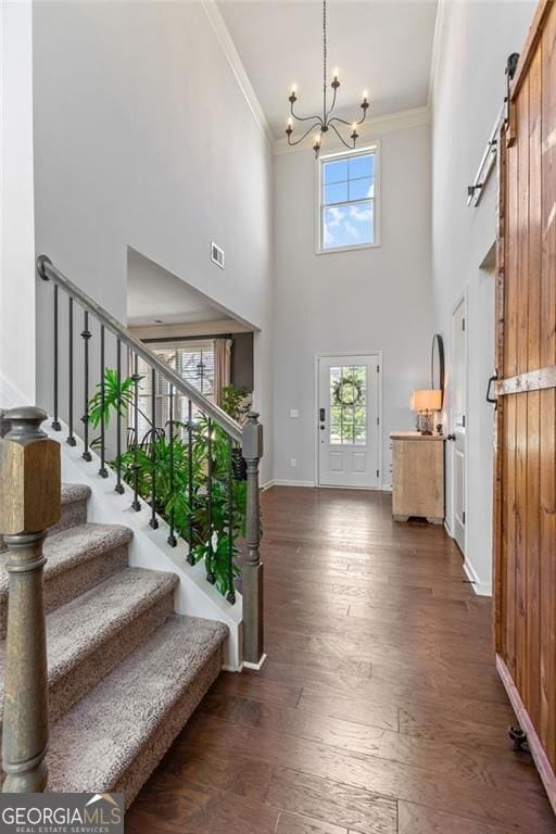 entryway with crown molding, visible vents, a chandelier, and a barn door