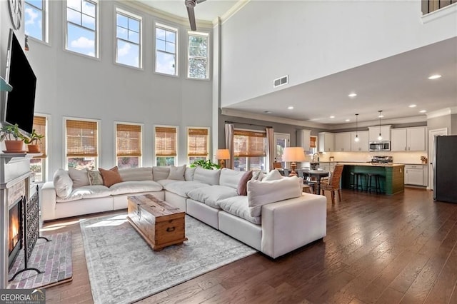 9085 Maple Run Trl, Gainesville, GA 30506 - living area featuring crown molding, a warm lit fireplace, a ceiling fan, a towering ceiling, and visible vents