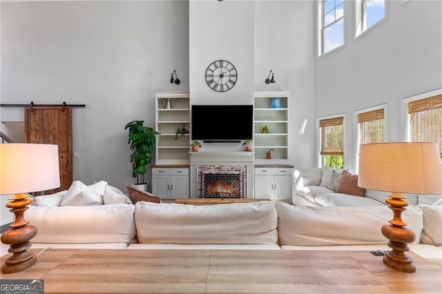 living room featuring a towering ceiling, a lit fireplace, and a barn door