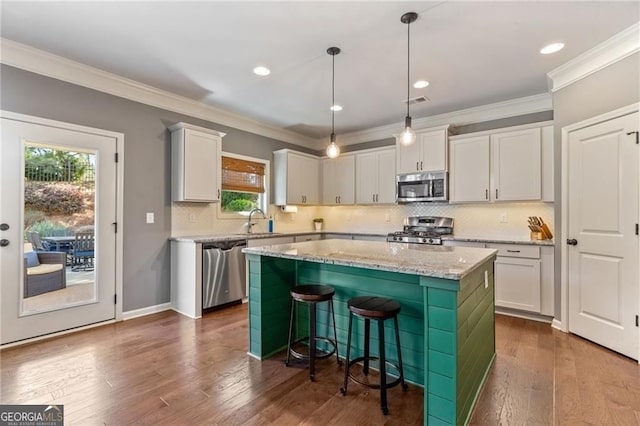 kitchen featuring a kitchen breakfast bar, a sink, a kitchen island, decorative backsplash, and appliances with stainless steel finishes