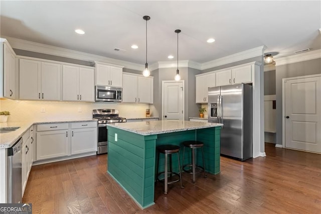 kitchen with white cabinets, stainless steel appliances, a center island, dark wood-style flooring, and ornamental molding
