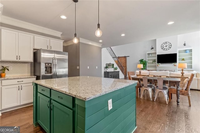 kitchen with a barn door, wood finished floors, stainless steel fridge, white cabinetry, and ornamental molding