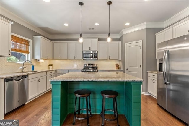 9085 Maple Run Trl, Gainesville, GA 30506 - kitchen with appliances with stainless steel finishes, a center island, white cabinets, dark wood-style floors, and ornamental molding