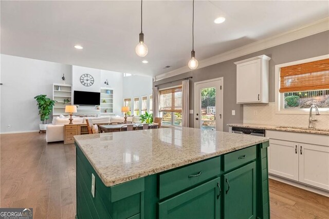 kitchen with white cabinets, a sink, green cabinetry, backsplash, and a kitchen island