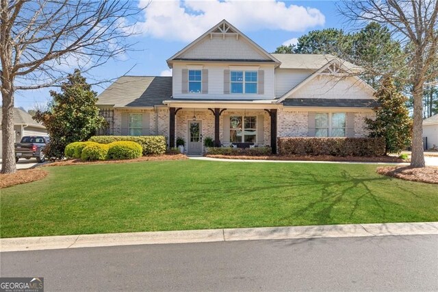 craftsman house featuring brick siding and a front yard