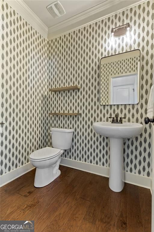bathroom with wood finished floors, baseboards, toilet, ornamental molding, and visible vents