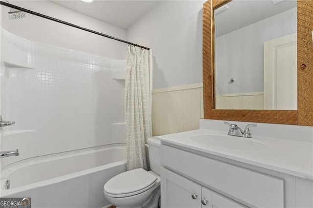 full bathroom with shower / bath combo with shower curtain, a wainscoted wall, vanity, and toilet
