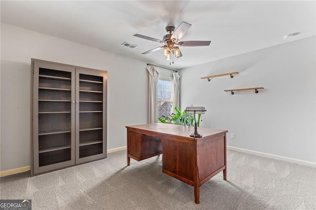 home office with light carpet, a ceiling fan, visible vents, and baseboards