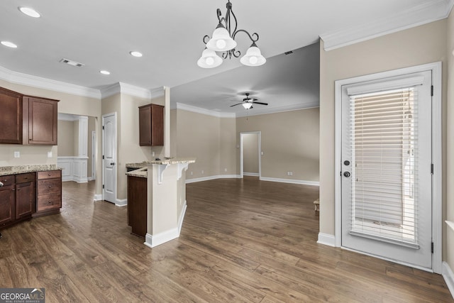 kitchen with crown molding, a peninsula, a kitchen breakfast bar, dark wood-style floors, and a ceiling fan