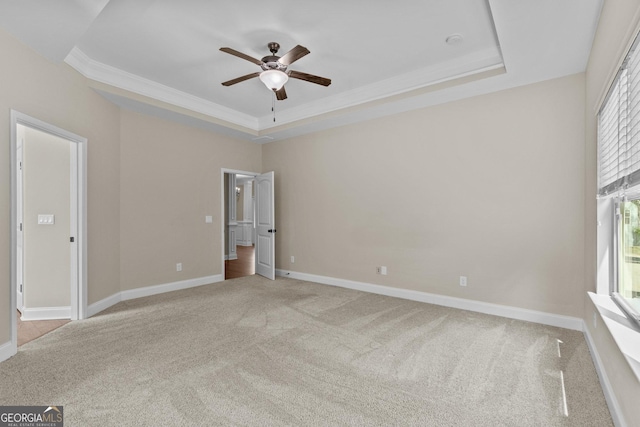 unfurnished bedroom featuring a raised ceiling, ornamental molding, and light carpet