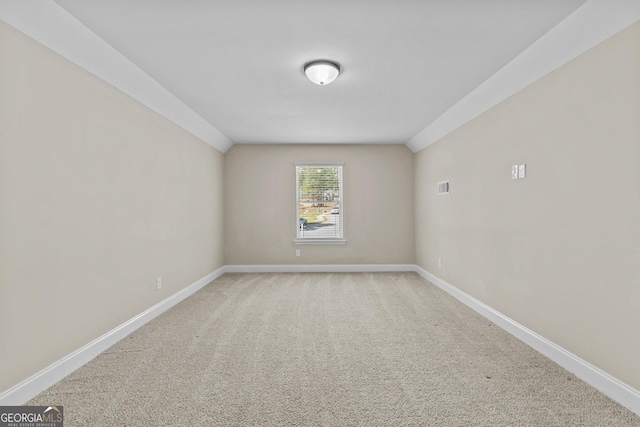 unfurnished room featuring light colored carpet, baseboards, lofted ceiling, and visible vents