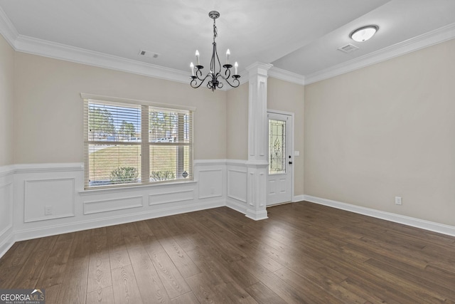 unfurnished dining area with visible vents, ornamental molding, wainscoting, a chandelier, and dark wood finished floors
