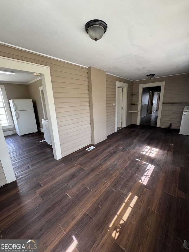 unfurnished living room with visible vents, ornamental molding, and wood finished floors