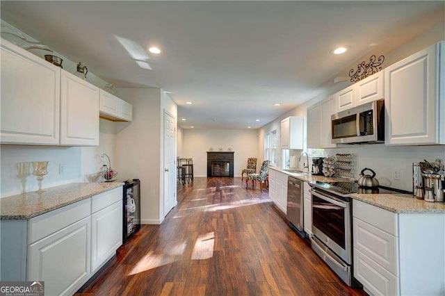 77 Hunters Grn, Dallas, GA 30157 - kitchen with a sink, dark wood-style floors, white cabinetry, stainless steel appliances, and a fireplace