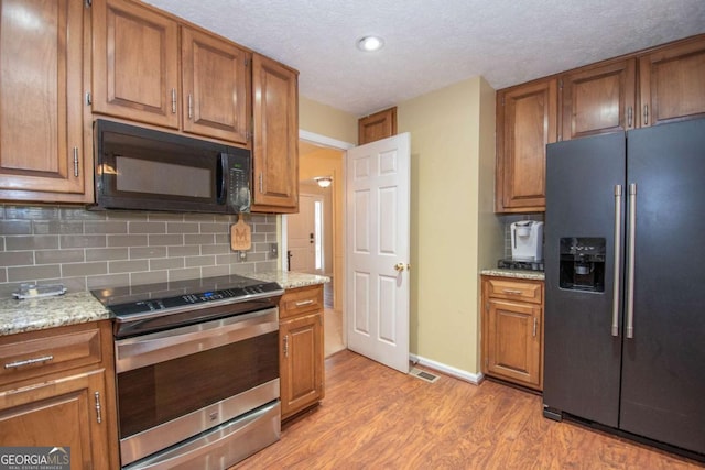 207 Lakeshore Way, Lagrange, GA 30240 - kitchen featuring refrigerator with ice dispenser, black microwave, electric stove, light wood-style floors, and brown cabinets