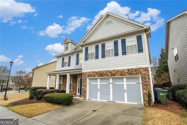 view of front of home featuring stone siding, an attached garage, and concrete driveway