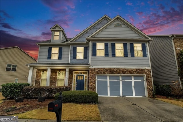view of front of house with stone siding, an attached garage, and driveway