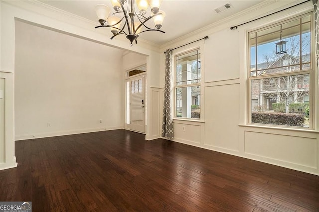 interior space featuring visible vents, dark wood-type flooring, crown molding, a decorative wall, and a chandelier