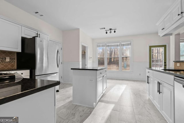 675 Timber Ives Dr, Dacula, GA 30019 - kitchen with stainless steel appliances, dark countertops, light marble finish flooring, a wainscoted wall, and a center island