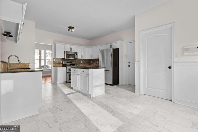 675 Timber Ives Dr, Dacula, GA 30019 - kitchen featuring appliances with stainless steel finishes, dark countertops, a sink, white cabinets, and light marble finish flooring