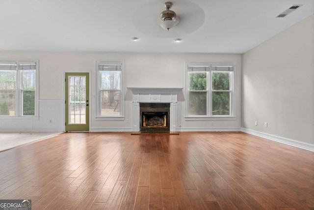 675 Timber Ives Dr, Dacula, GA 30019 - unfurnished living room featuring ceiling fan, a fireplace with raised hearth, wood finished floors, healthy amount of natural light, and wainscoting