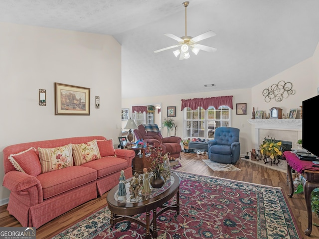 living room featuring visible vents, a ceiling fan, wood finished floors, a fireplace, and vaulted ceiling