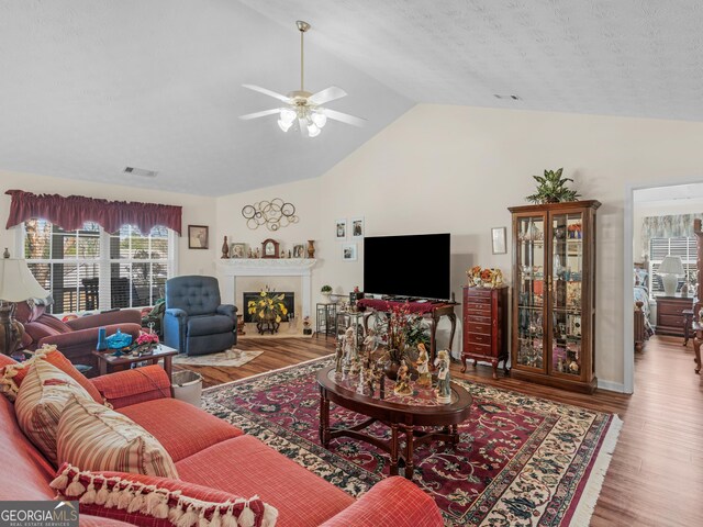 living room with visible vents, a ceiling fan, wood finished floors, a fireplace, and lofted ceiling