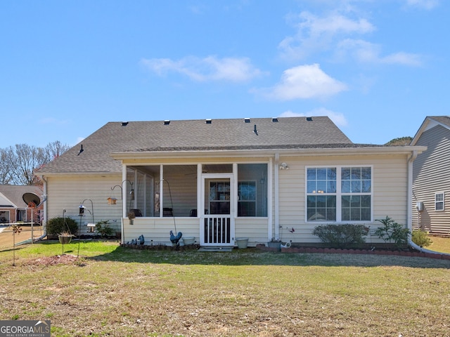 rear view of house with a shingled roof, a yard, and a sunroom
